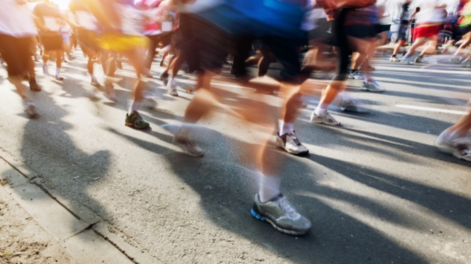 Marathon runners in motion. Running in the city, sun shining.